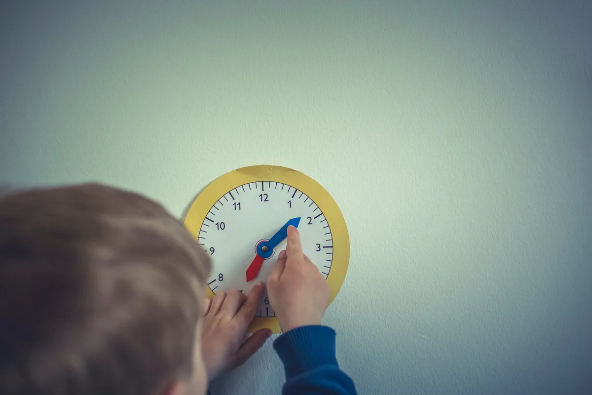 A child moving the hands of a toy clock